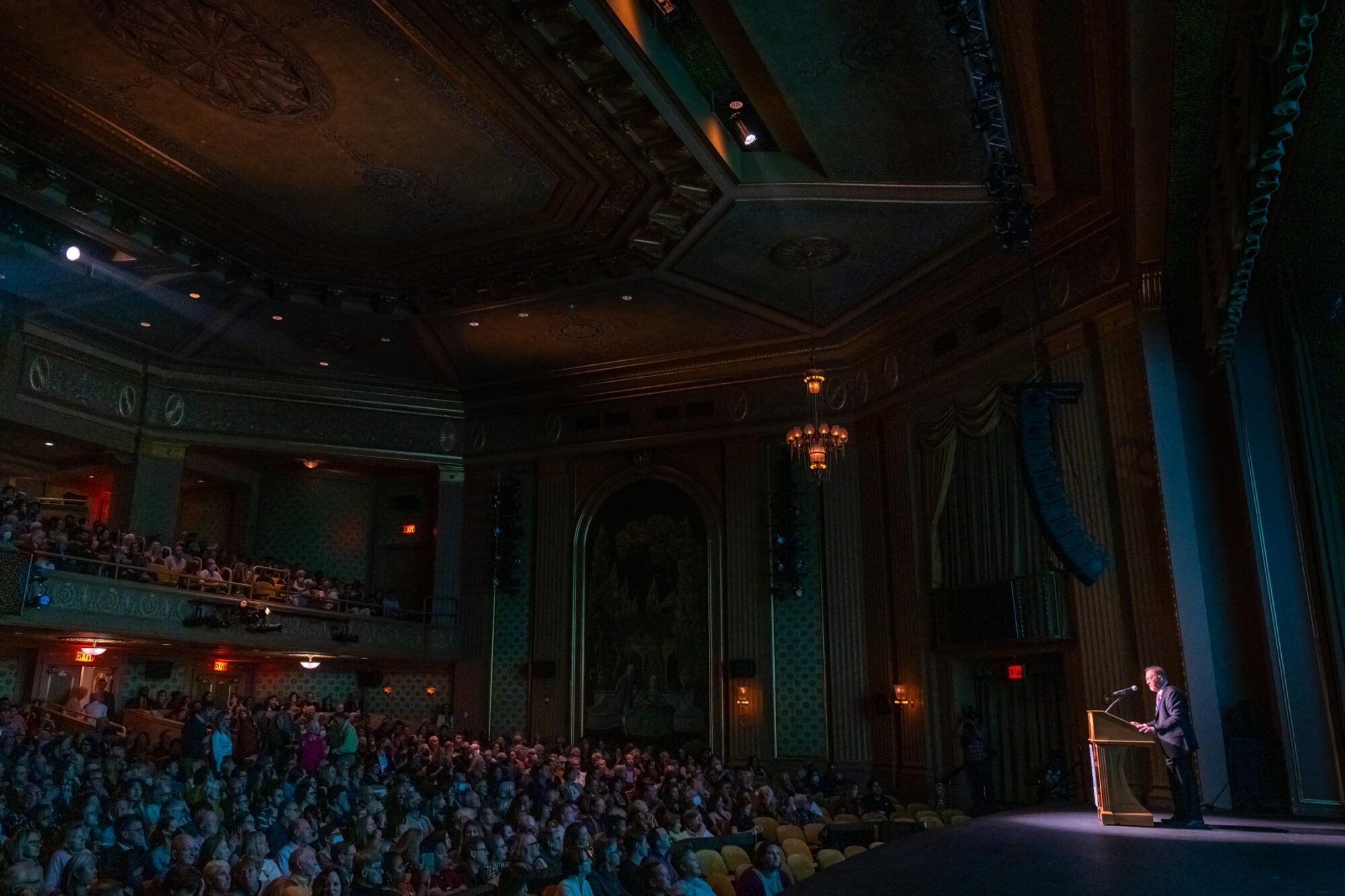 Packed theater at film festival opening night, audience watching speaker on stage.
