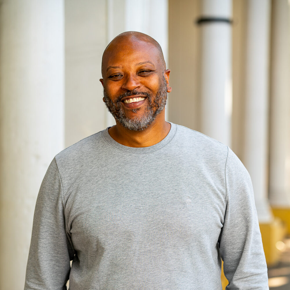 Portrait of Ty Cooper smiling outdoors with white columns in the background.