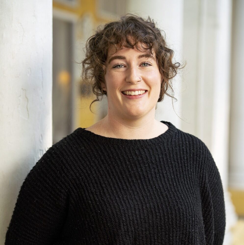A headshot of Kerry Reichhardt smiling, standing in front of white columns.