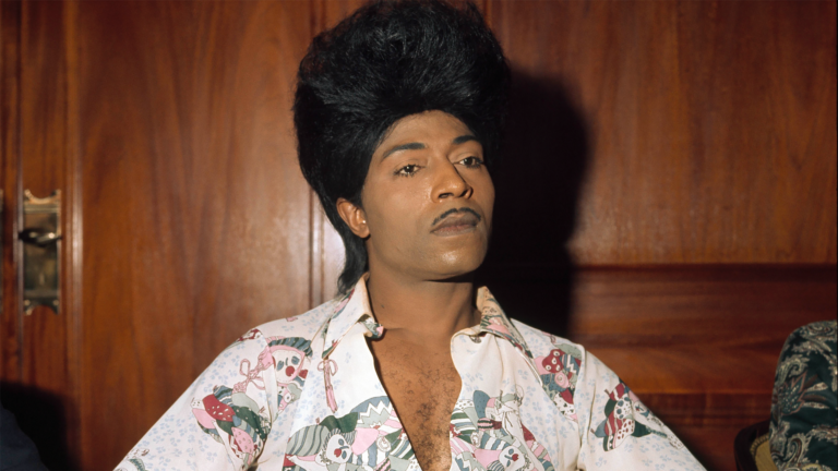 Little Richard with his signature pompadour hairstyle and mustache, wearing a patterned shirt.