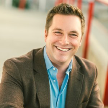 Perrin Chiles smiling in a brown blazer and blue shirt.