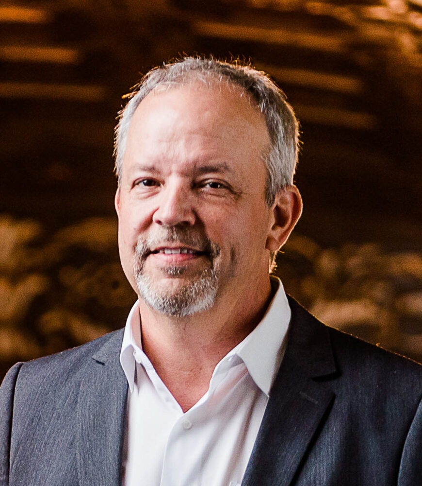 Andy Edmunds, headshot with a gray suit and goatee, smiling