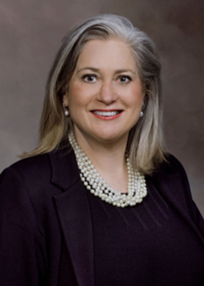 Linda Stanley, portrait of a professional woman in a dark blazer and pearl necklace.