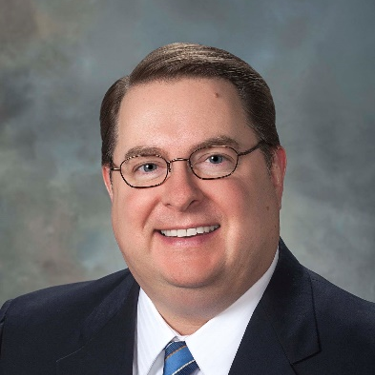 Headshot of John L. Mitchell, wearing glasses and a suit.