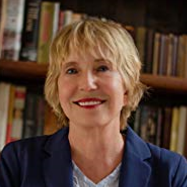 Sara Risher, author and speaker, smiles in front of a bookshelf.