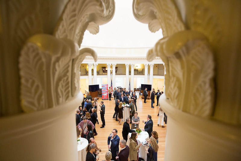 People at a fundraising event, seen through ornate architecture.