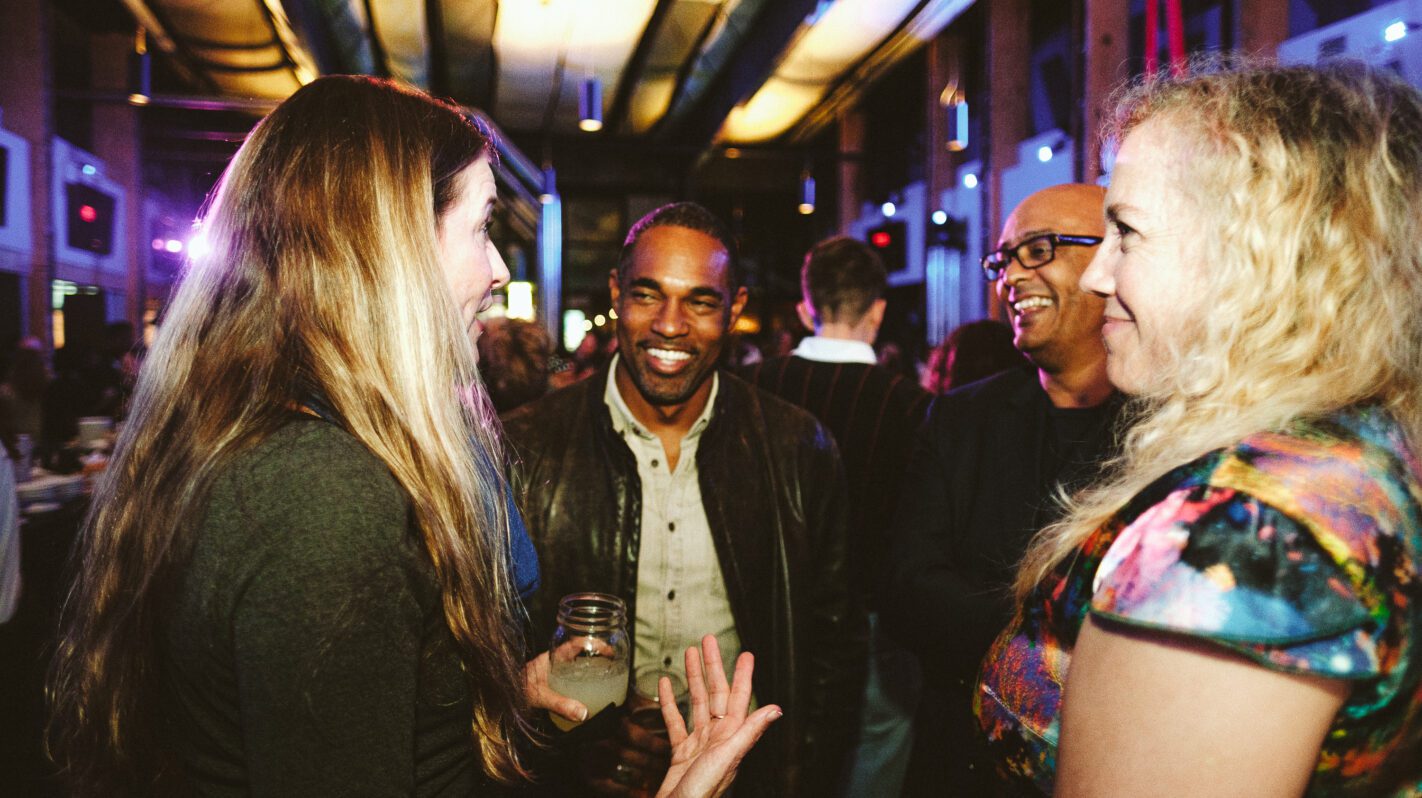 People networking at a corporate event, smiling and engaged in conversation.