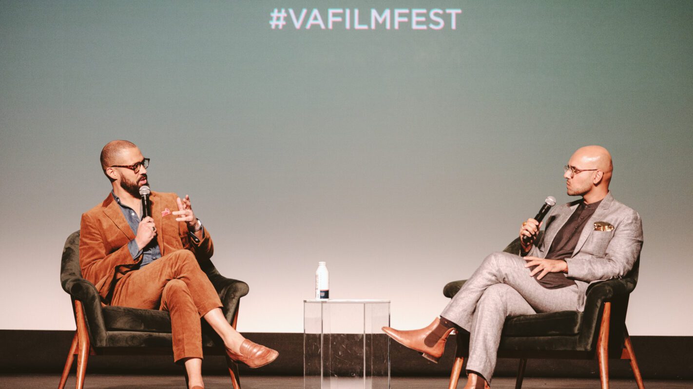Two men in suits speaking at #VAFilmFest, discussing donor benefits.