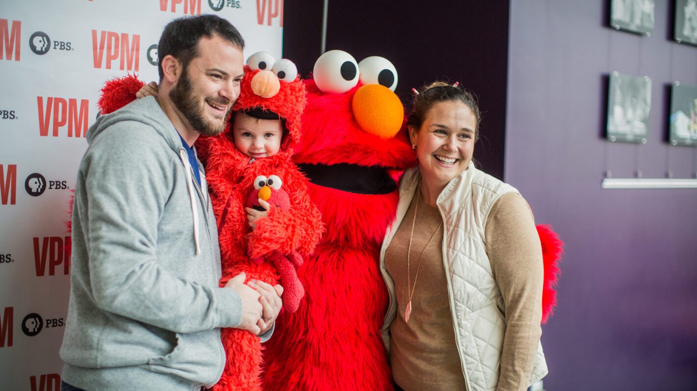 Family with Elmo mascot at PBS VPM event.