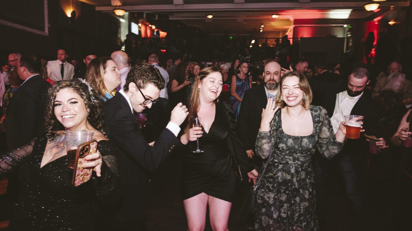 People laughing and dancing at a lively indoor party or event.
