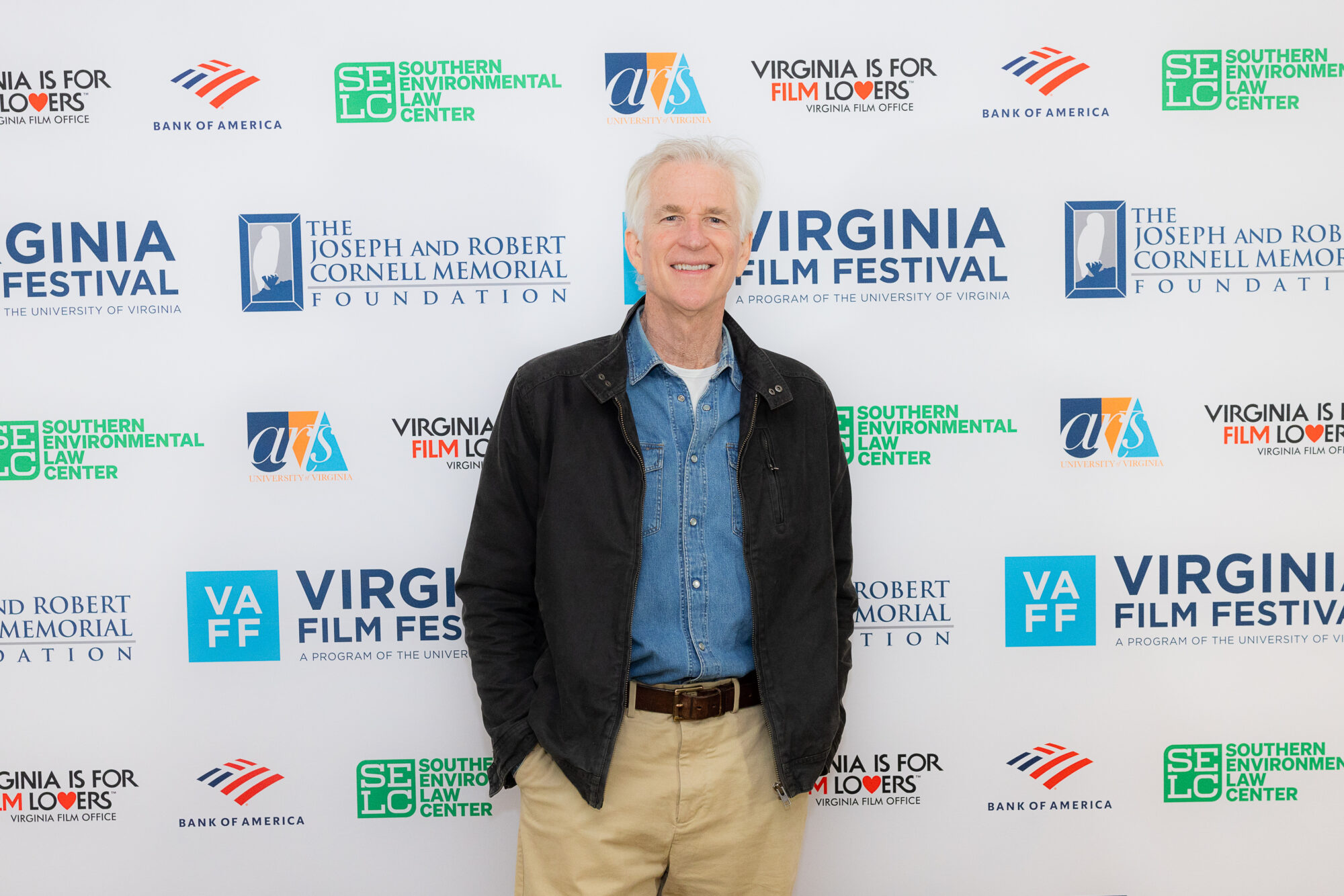 Man at the Virginia Film Festival, a program of the University of Virginia. Event sponsors are visible in the background.