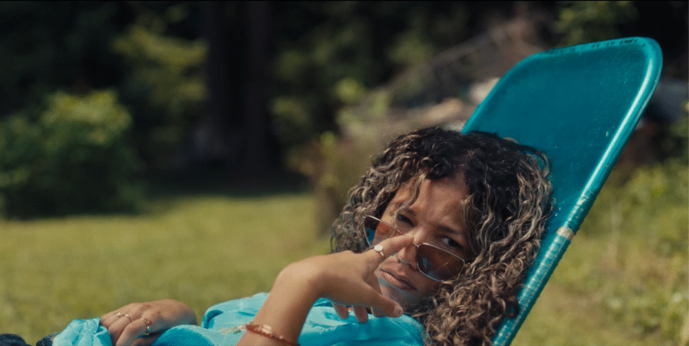 Woman in sunglasses lounging in a blue chair outdoors, relaxed and enjoying the moment.