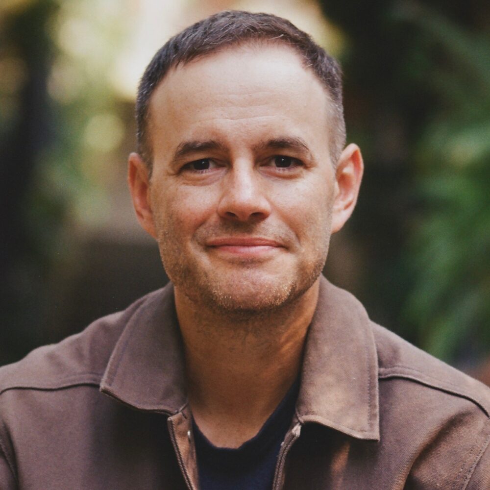Clay Tweel, headshot of a man with short hair and a brown jacket.
