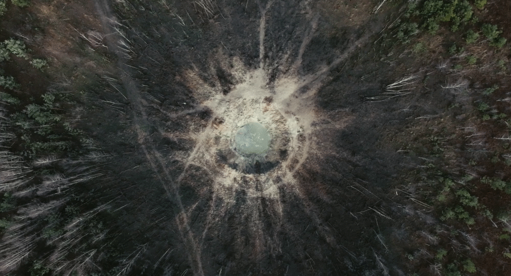 Aerial view of a large impact crater in a forest, revealing the power of nature.