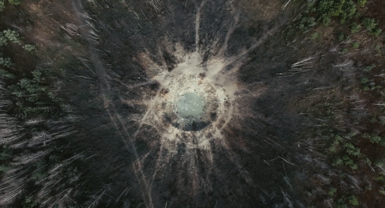 Aerial view of a large impact crater in a forest, revealing the power of nature.