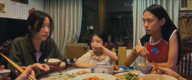 Three Asian girls eating dinner together at a table.