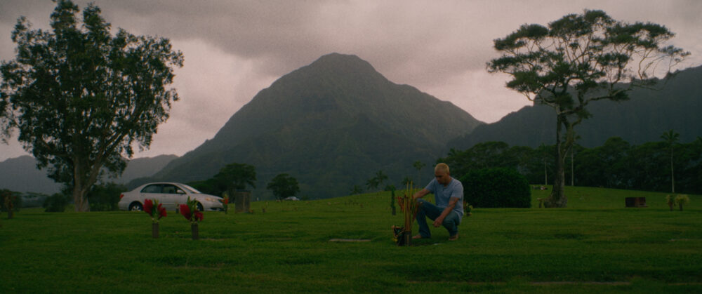 Man at gravesite with mountains in background
