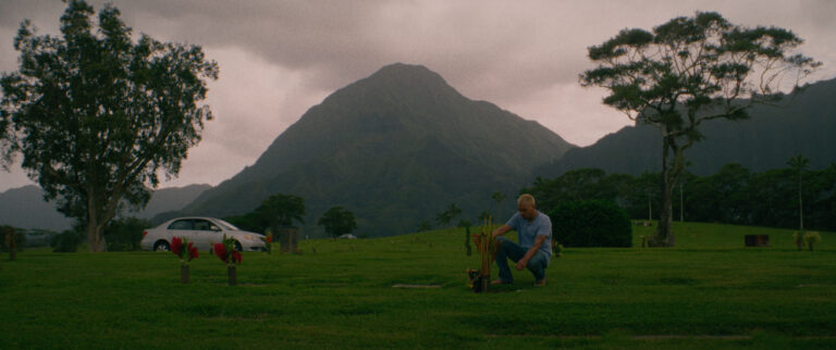 Man at gravesite with mountains in background