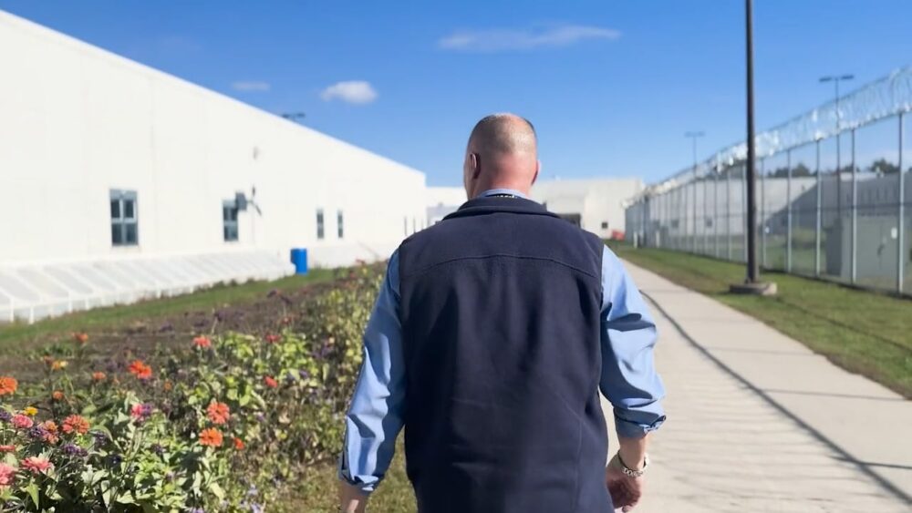 Man walking toward a correctional facility, "On Beyond Fences