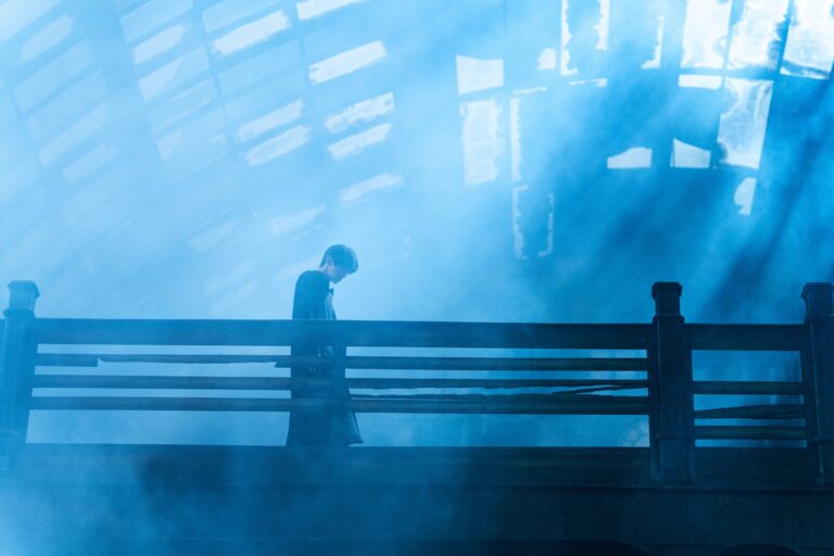 Man standing on wooden bridge with blue fog in background