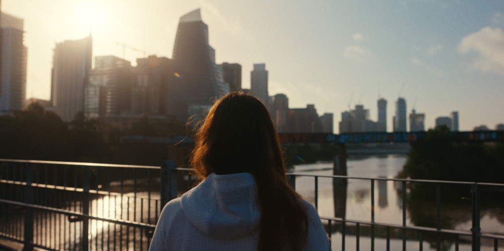 Woman looks out at the Austin, Texas skyline at sunrise.