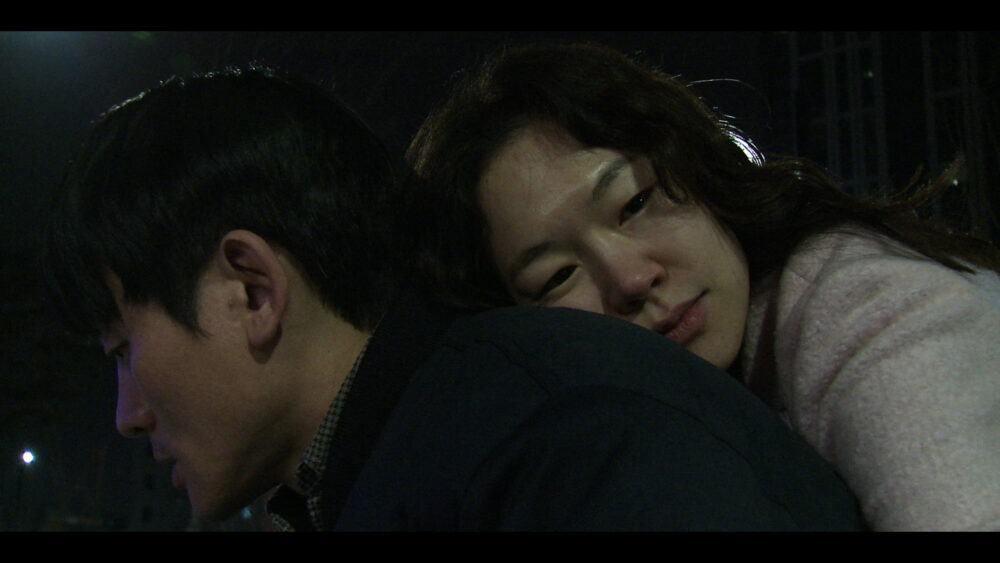 Woman rests head on man's shoulder in a scene from "Spring Night.