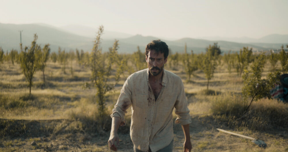 Man with bloodstains in a field, possibly from "The Things You Kill.