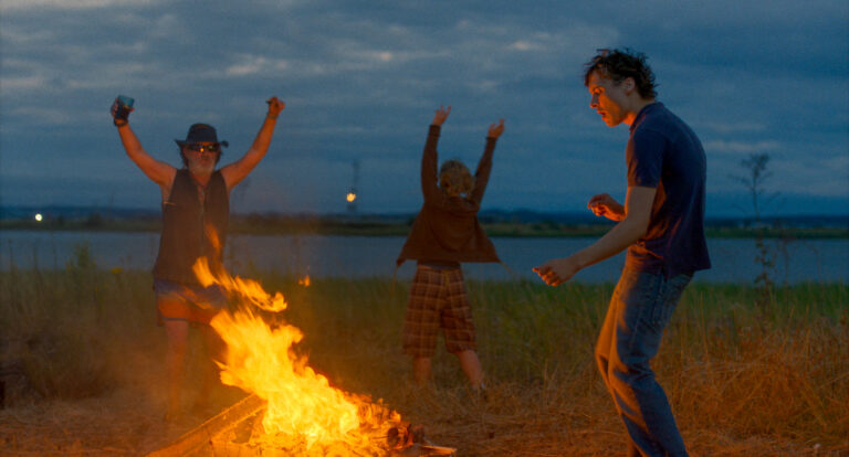 People around a bonfire at dusk. The image relates to the blog, Urchin.