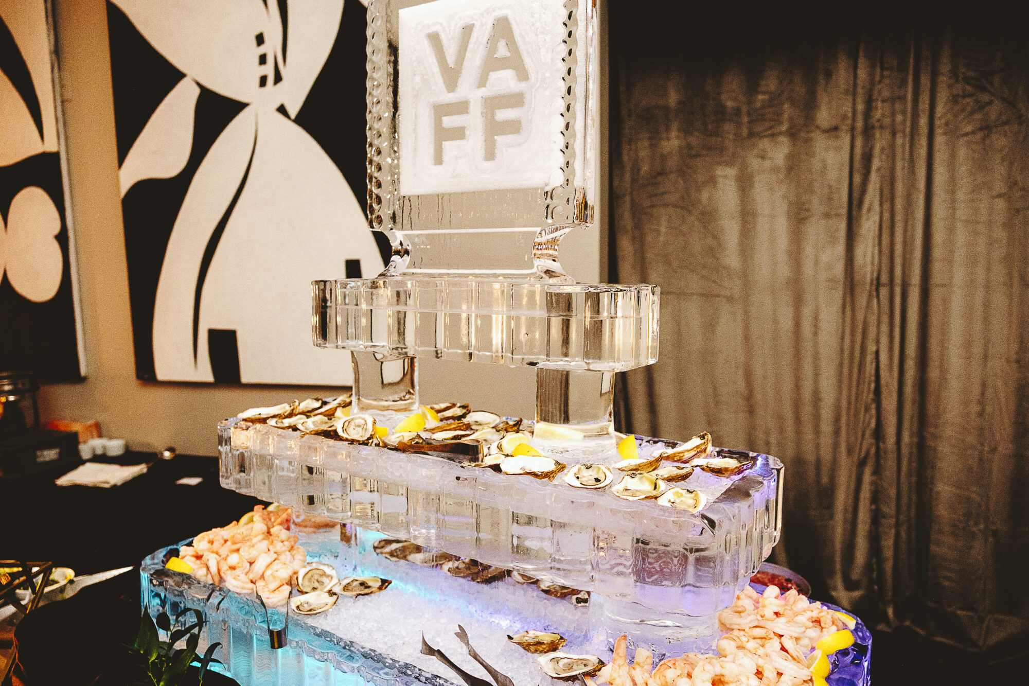 Ice sculpture with VAFF logo, oysters, and shrimp at an event